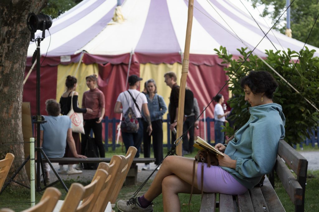 Auf dem Bild ist eine Person zu sehen, die auf den Holzstühlen des Outdoor-Festivalkinos sitzt.